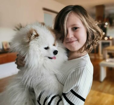 Ein Mädchen, dass einen weißen Hund auf dem Arm hält. 